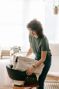 Mujer ordenando y preparando el lugar para hacer una sesión de fotografías en el interior de un inmueble